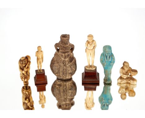 A carved ivory Netsuke,&nbsp;in the form of a street vendor; three other ivory figures; an Egyptian Ushapti figure; and a sma