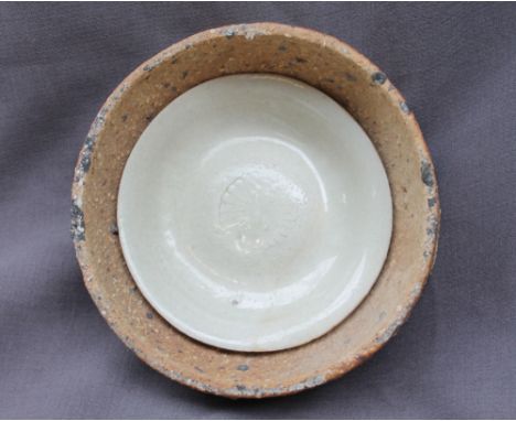A Song dynasty Qingbai porcelain dish, with a light green glaze fused to the kiln saggar, 14cm diameter, saggar 19cm diameter