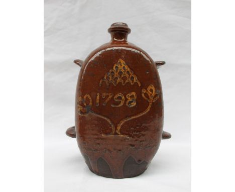 An 18th century slipware flask, of rectangular form, having four ring handles with a brown glaze and mustard yellow decoratio