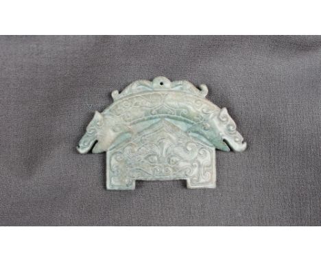 A Chinese green hardstone tablet possibly jade, of arched form, carved with a double headed dragons, mask and scrolls 93mm x 