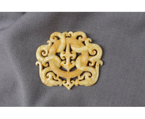 A Chinese yellow hardstone tablet possibly jade of oval form, carved with interlaced dragons and a twisted roundel, 77mm x 66