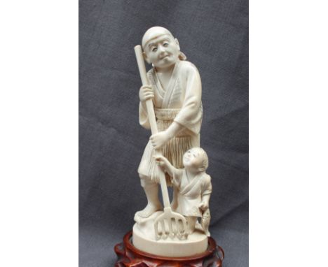 A 19th century ivory figure group of a man and child holding a five point fishing trident, signed to the base, 18cm high 