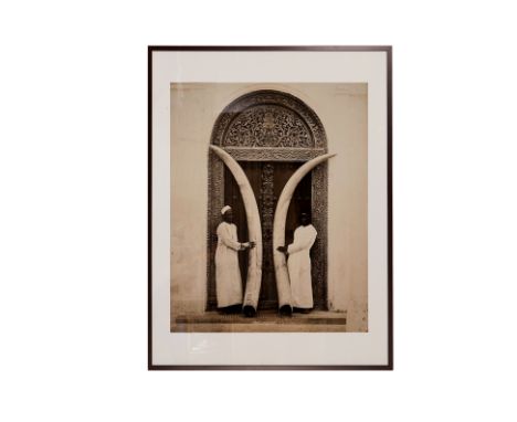 TWO IVORY TUSKS, ZANZIBAR FRAMED POSTER
Reproduction print of the photograph by A.C. Gomes &amp; Son, c. 1910
96cm x 76cm; wi