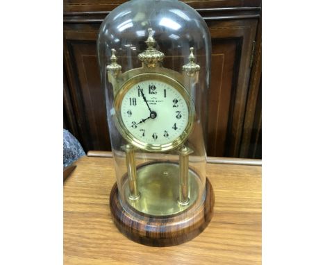 A anniversary clock under glass dome the circular dial with Arabic numerals.