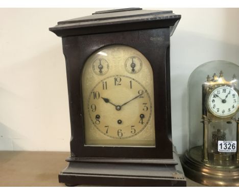 A mahogany mantle clock the silver dial with Arabic numerals.