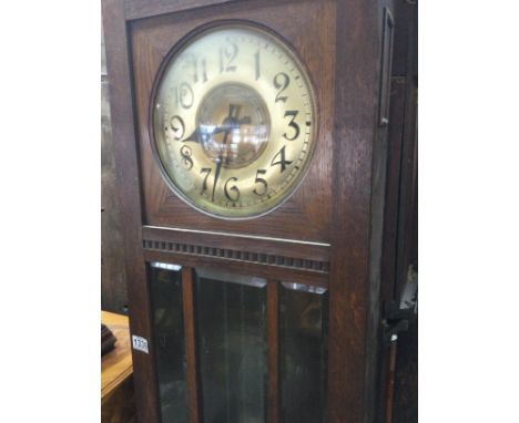 A oak long case 30 hour clock the circular dial with Arabic numerals visible Weights and pendulum.