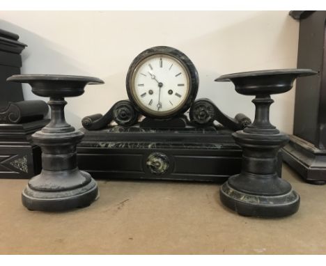 A marble clock with Roman numerals with a pair of side ornaments.