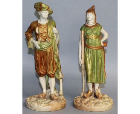 A PAIR OF ROYAL WORCESTER GILT FIGURES OF A TURK AND HIS WIFE, No. 1243, standing on circular rustic bases. 9.5ins high.