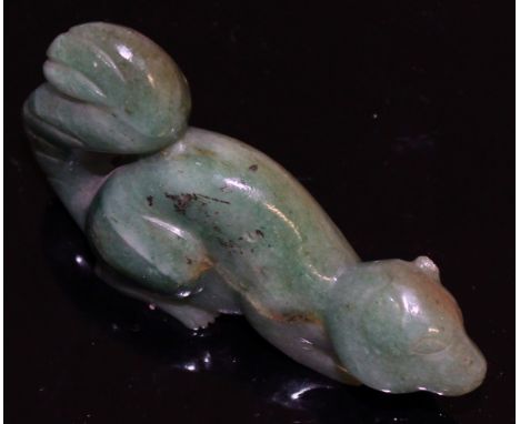 A 20TH CENTURY CHINESE GREEN JADE-LIKE CARVING OF A SQUIRREL, the stone with lighter inclusions and striations, 3.1in long.