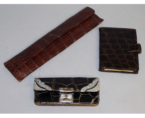 A SILVER MOUNTED CROCODILE PURSE, a silver mounted comb in a leather case and a crocodile notebook (3).