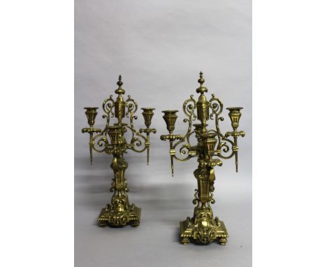 A PAIR OF CONTINENTAL BRASS FOUR LIGHT CANDELABRA. 1ft 6ins high.