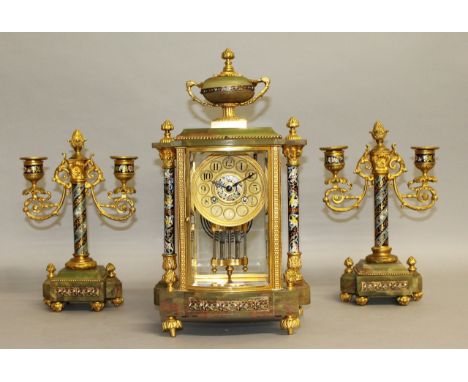 A GOOD 19TH CENTURY FRENCH GREEN ONYX AND CHAMPLEVE ENAMEL THREE PIECE CLOCK GARNITURE, the clock with urn finial, column sup