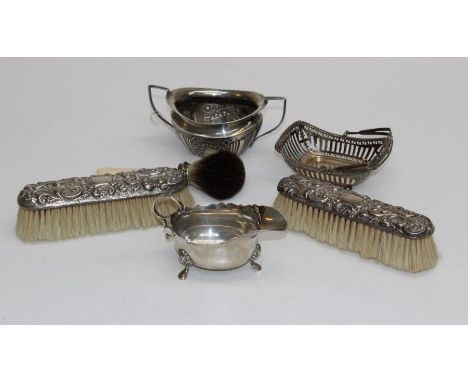A pair of embossed silver mounted brushes, Birmingham 1898, a small swing handled pierced basket, a George III style small si