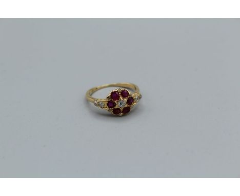 &nbsp;A yellow metal (tested as 18carat) ruby and diamond daisy ring set with six small rubies and five graduated eight cut d