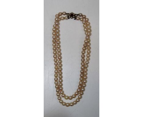 A double stranded pearl choker with a yellow metal clasp, stamped 9ct and&nbsp; set with split pearls and a central garnet.