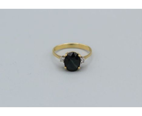 A yellow metal ring with a large low quality green/blue sapphire and two 2mm diamond, shank stamped 750&nbsp;