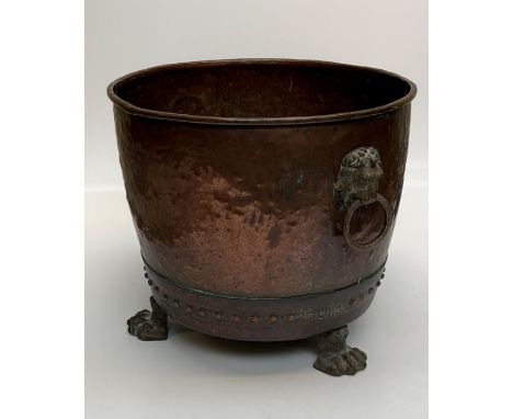 A large Victorian country house copper log bin of rivited construction, with twin lion's mask ring handles, raised on hairy p