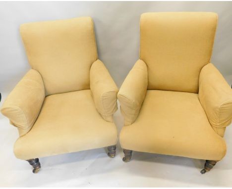 A pair of Victorian mahogany armchairs, in Howard style, upholstered in beige fabric, on turned tapering legs with ceramic ca