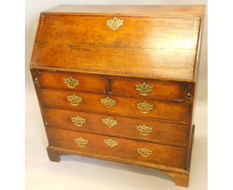 A George III oak and mahogany cross banded bureau, the fall enclosing a fitted interior above two short and three long drawer