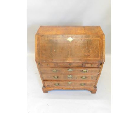 A small walnut bureau in mid 18thC style, the fall with a cross banded border enclosing a fitted interior above three short d