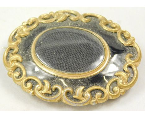 A Victorian memorial brooch, of oval with central memorial panel, surrounded by scroll border, on black enamel background, on