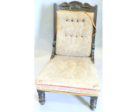 A Victorian mahogany nursing chair, with a carved show frame, button back, padded seat, on turned legs