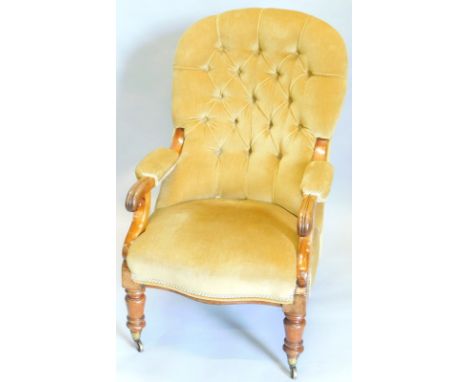 A Victorian mahogany open armchair, with a button padded back, armrests and seat, scroll carved arm supports, on turned legs 