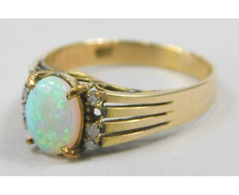 A dress ring, set with oval opal, flanked by four tiny diamonds to each side (1 missing), with four row layered sides, yellow