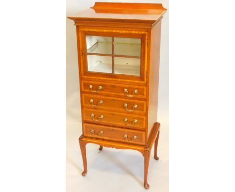 An Edwardian mahogany and satinwood cross banded music cabinet, with a glazed door enclosing a single glass shelf, above four