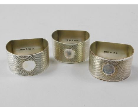 A set of three silver George V engine turned D-shaped napkin rings, each with a circular vacant cartouche, in a fitted case, 