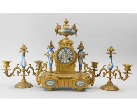 A French late 19thC gilt metal and porcelain clock garniture, the clock mounted with an urn above a ceramic dial painted with