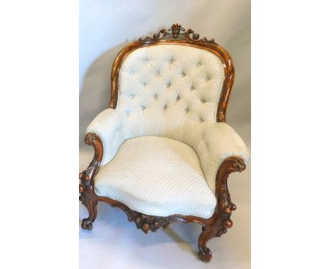 A Victorian walnut show frame armchair, with a button back, padded arms and seat on cabriole supports carved with fruit etc.