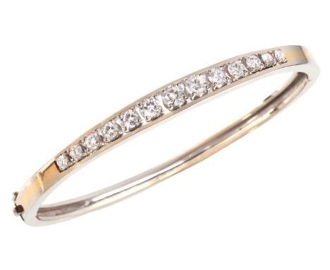 A HINGED DIAMOND BANGLE in 18ct gold, set with a row of round brilliant cut diamonds, totalling c.1.50 carats, secured with a