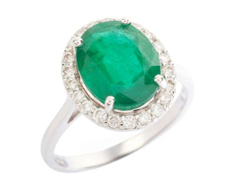AN EMERALD AND DIAMOND CLUSTER RING in 18ct white gold, set with an oval cut emerald of c.3.33 carats, surrounded by a cluste