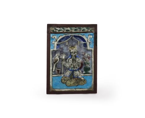 A Qajar tile, 19th century, the rectangular form moulded with a figure kneeling and holding a staff with a cow's head before 