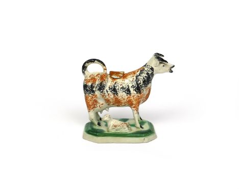 A creamware cow creamer and cover, c.1800-10, standing four square on an octagonal base, a recumbent calf between her feet, h