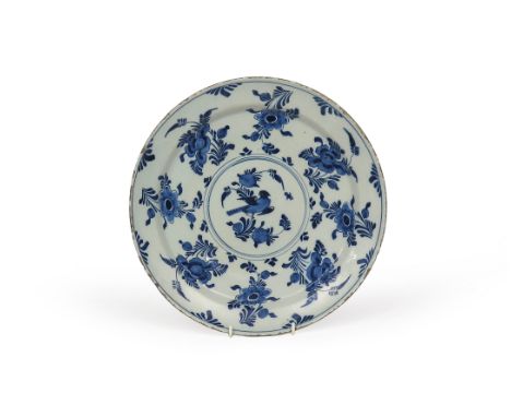 A large delftware charger, c.1740, painted in blue with a bird perched on a flowering branch, within a circular panel, the wi