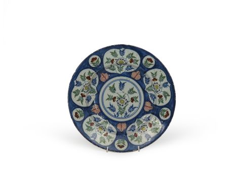 A delftware plate or charger, c.1720, probably Bristol, painted with five shaped panels around a central roundel containing f