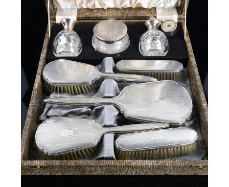 A cased George VI silver dressing table set, comprising hand mirror, 2 x hair brushes, 2 x clothes brushes, glass atomiser an