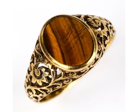 A large unmarked gold tigers eye dress ring, with pierced foliate shoulders and bridge, setting height 13.1mm, size V, 5gNo d