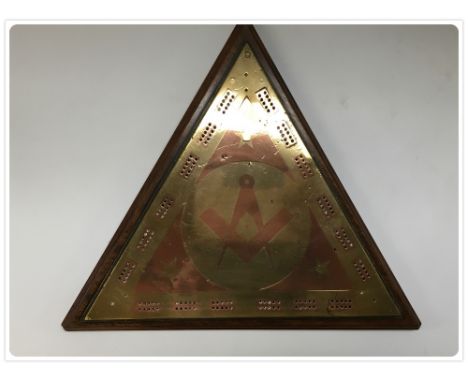 A 19TH CENTURY TRIANGULAR BRASS AND COPPER CRIBBAGE BOARD WITH MASONIC DIVIDER MOTIF TO CENTRE MOUNTED ON MAHOGANY BASE 