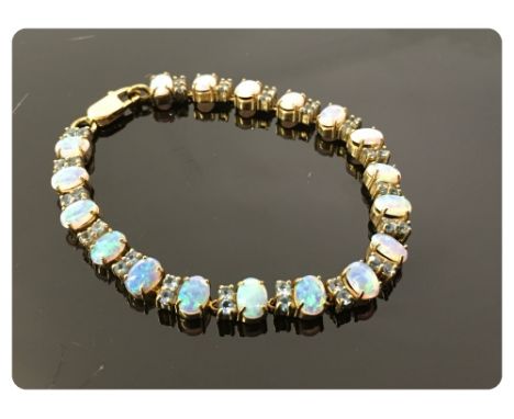 A 9CT GOLD TENNIS BRACELET SET WITH EIGHTEEN OVAL OPALS, ALL CLAW SET, DIVIDED BY PAIRS OF SMALL BLUE STONES (ONE OPAL CRACKE