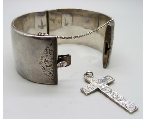 An engraved silver bangle and a silver cross, 3.5cm bangle width, 72g total