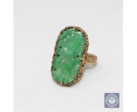 A Chinese silver gilt carved jade ring CONDITION REPORT: 7.0g. In good condition. There is a maker's mark to the shank. 