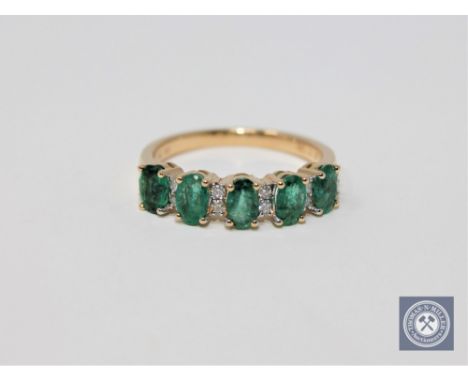 A 14ct yellow gold emerald and diamond ring featuring 5 oval cut natural diamonds 1.21ct, 12 round brilliant cut diamonds 0.1