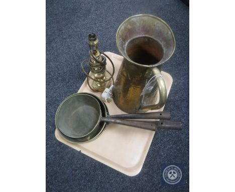 A tray of brass table lamp, brass jug and three cast iron handled sauce pans 