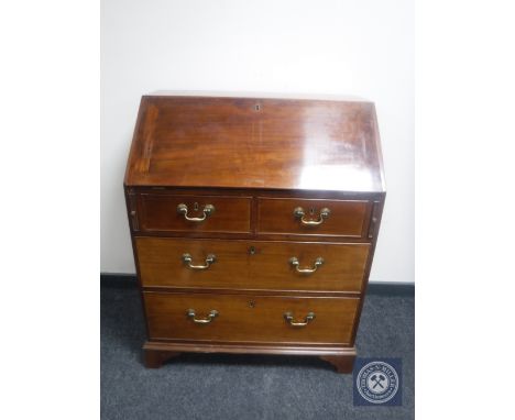 An antique mahogany writing bureau fitted four drawers with brass drop handles on bracket feet