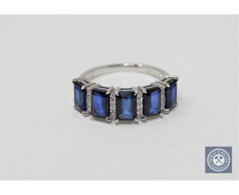 A 14ct white gold sapphire and diamond ring featuring 5 emerald cut natural sapphires 2.91ct with 24 round brilliant cut diam