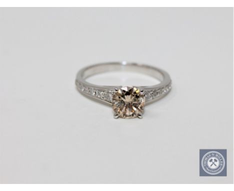 A 14ct white gold diamond solitaire ring featuring one round brilliant cut diamond 1.02ct with 14 round brilliant cut diamond
