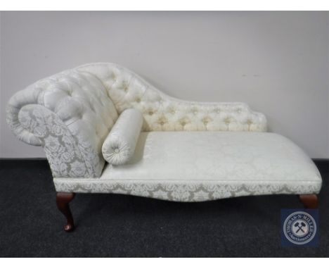 A contemporary chaise longue upholstered in a cream buttoned floral print